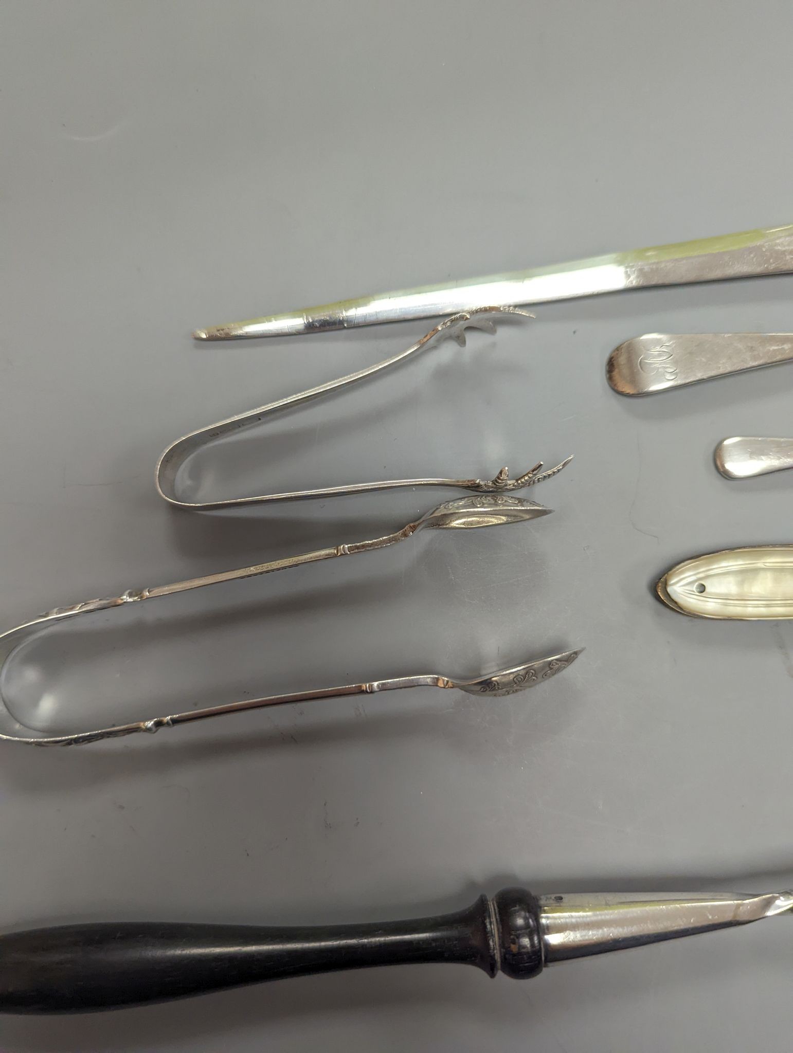 A George VI silver paper knife, London, 1937, a plated toddy ladle, two pairs of silver sugar tongs, damaged silver fruit knife and two other items.